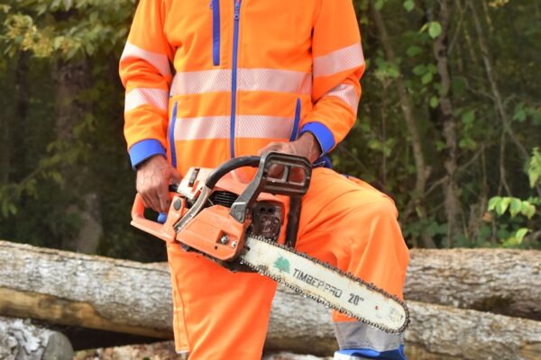a man in an orange safety suit holding a chainsaw